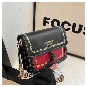 Detail of contrast stitching and wide jacquard strap on a luxury leather crossbody bag