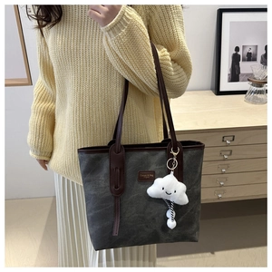 Detail of dark grey canvas tote bag with brown leather trim and cute plush cloud charm