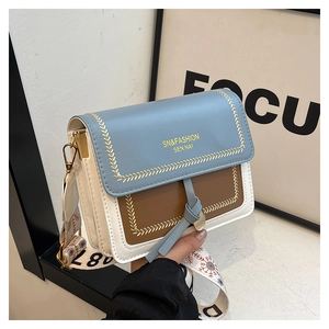 Detail of color-block flap bag with patterned wide strap and gold hardware accents