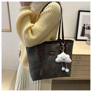 Detail view of large grey tote bag with brown handles and a cute white cloud charm