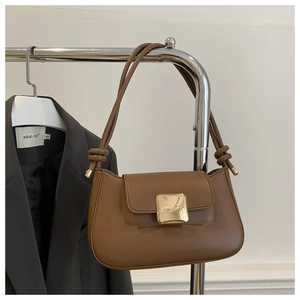 Detail view of caramel brown shoulder bag featuring gold square buckle and knotted strap