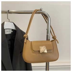 Detail of camel underarm bag featuring a gold square buckle and knotted strap design