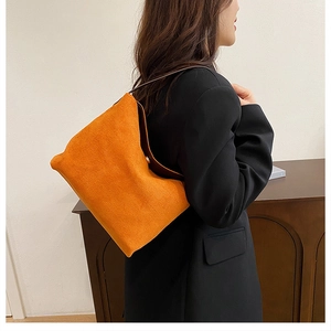 Détail d'un sac cabas en daim orange vif avec boucle en métal doré et bandoulière marron