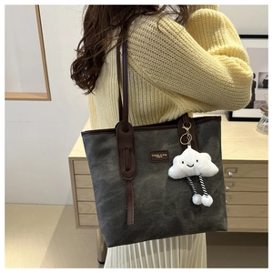 Large vintage charcoal tote bag with brown straps and plush cloud charm on a model