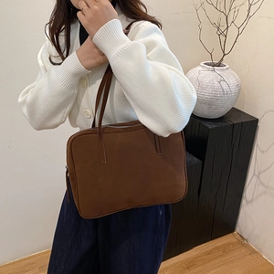 Brown suede tote bag styled with minimalist interior decor on a model shoulder