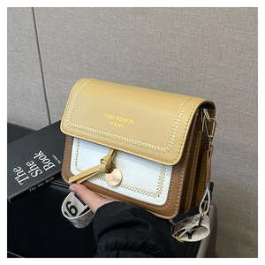 Detail of color-block crossbody bag with yellow flap, white surface, and printed wide strap