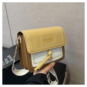 Detail of yellow and white crossbody bag with wheat stitching and embroidered wide strap