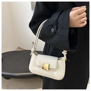 Close-up of cream white leather shoulder bag featuring square gold clasp and knot strap detail