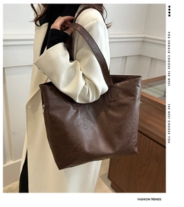 Detail of dark brown tote bag with crinkled leather texture worn on shoulder