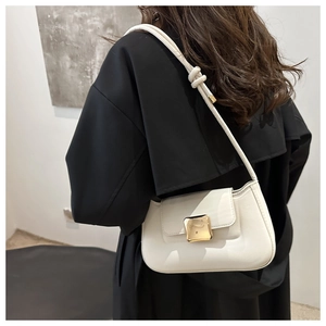 Detail of white minimalist shoulder bag featuring large gold square buckle and knotted strap