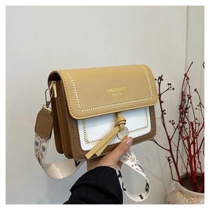 Detail of color-block crossbody bag with knotted strap and gold hardware accents