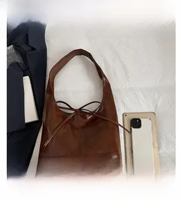 Macro detail of dark brown tote bag showing high-gloss PU leather and bow tie decoration