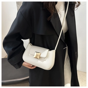 Close-up of white minimalist shoulder bag featuring a square gold buckle on a model