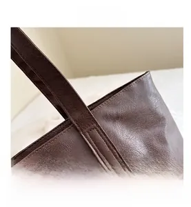 Detail view of reinforced stitching and waxed leather texture on a dark brown tote bag