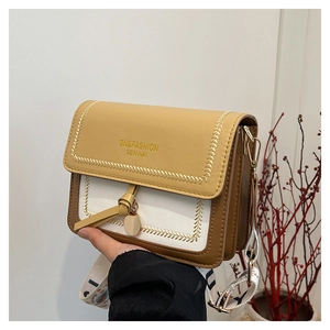 Detail of color-block crossbody bag with wheat-stitch trim and printed wide strap