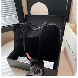 Detail of minimalist black suede shoulder bag with long straps and silver zipper