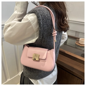 Detail of light pink shoulder bag featuring a gold square buckle and knotted strap design
