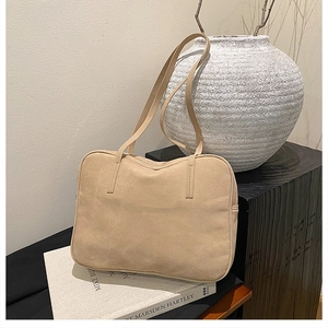 Detail of minimalist beige faux suede tote bag on book with rustic art props