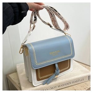 Detail of a color-block crossbody bag with embroidered strap and golden hardware