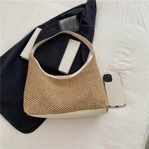 Detail of woven straw tote bag with white leather trim and strap on neutral background