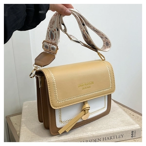 Detail of contrast flap on crossbody bag with wide embroidered ethnic shoulder strap