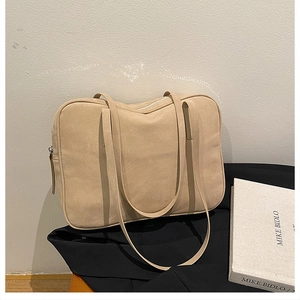 Detail of a large khaki suede tote bag with dual straps and silver metal zipper closure