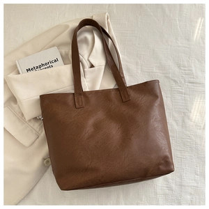 Detail of dark brown tote bag showing premium lychee grain leather texture and handle