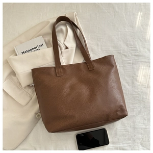 Brown faux leather tote bag with lychee texture arranged with a blazer and book