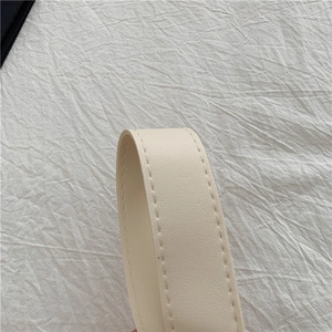 Detail of beige faux leather strap with precise stitching on a woven tote bag