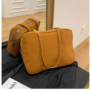 Detailed view of ginger brown suede tote bag with zipper closure on black silk fabric