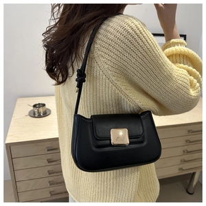 Detail of black matte leather underarm bag featuring a gold buckle and knotted strap