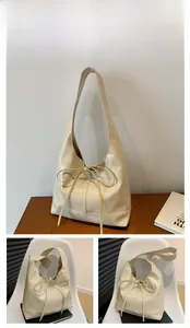 Detail shot of a cream-colored soft leather hobo tote bag with a decorative bow drawstring