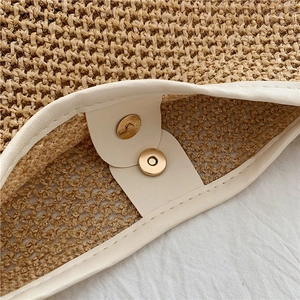 Detail of metal magnetic clasp and fine woven texture on straw tote bag