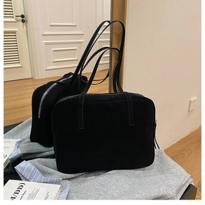 Detail of a black canvas tote bag with a zipper and slim shoulder straps for daily commute