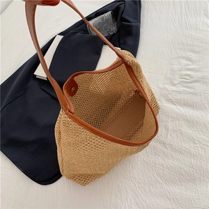 Detail of hand-woven straw tote with premium brown leather trim and metal magnetic closure