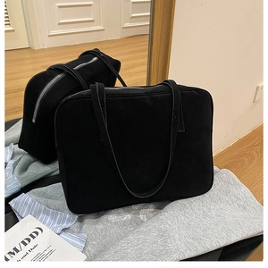 Detail of a black minimalist large capacity tote bag featuring long shoulder straps