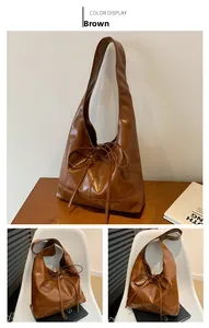 Detailed view of the large brown tote bag featuring a decorative long bow ribbon accent