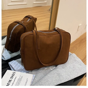 Detail view of large brown suede shoulder bag with dual handles and silver zipper closure