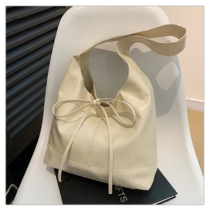 Macro view of cream white tote bag with soft pleated texture and ribbon bow detail