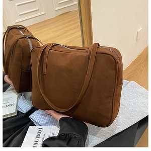 Close-up of the dark brown suede shoulder bag with dual straps and metal zipper detail
