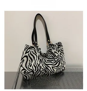 Detail showing zebra pattern canvas texture and golden metal ring strap attachment