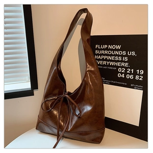 Close-up of dark brown wax leather hobo bag featuring a decorative bow tie and glossy texture