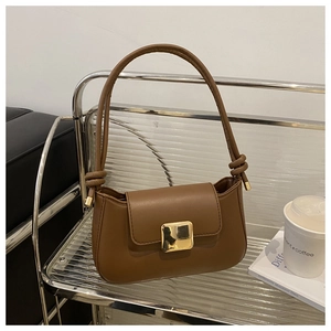 Detailed view of caramel brown crossbody bag with square gold buckle and knot strap detail