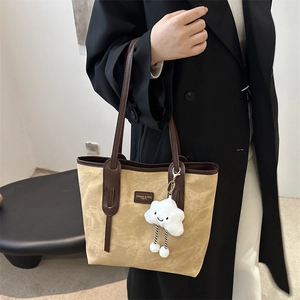 Minimalist beige canvas tote bag with brown leather handles and a plush cloud charm