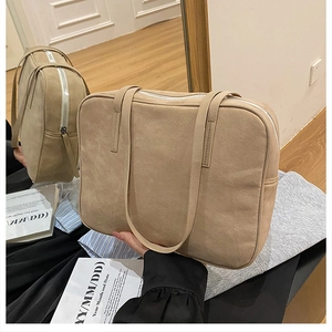 Detail view of beige matte suede tote bag featuring silver zipper and slim shoulder straps