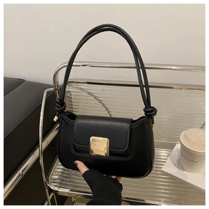 Detail of black matte shoulder bag with golden square buckle and knotted strap