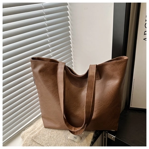 Detail of a large brown retro leather tote bag placed near a window with sunlight