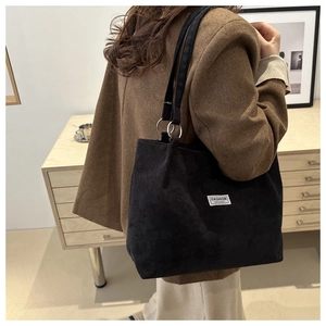 Detail of black corduroy tote bag featuring silver rings and Fashion Instinct label