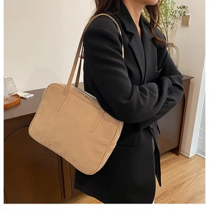 Close-up of khaki rectangular shoulder bag in faux suede with slim strap on a black blazer