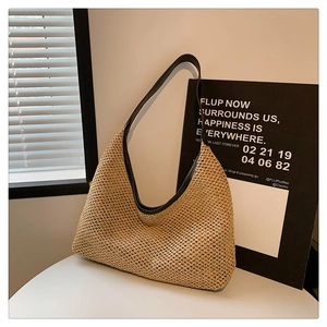 Detailed close-up of woven straw texture and black leather trim on a beige tote bag
